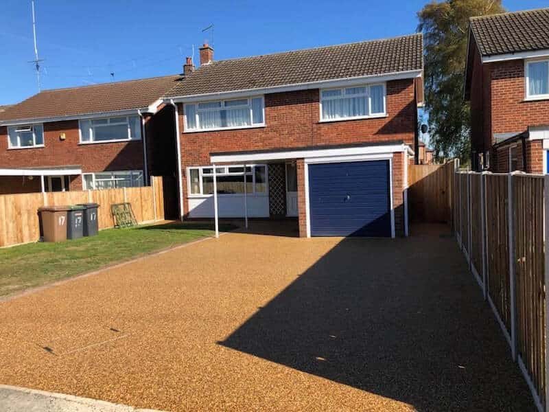 Warm golden resin driveway leading to a garage