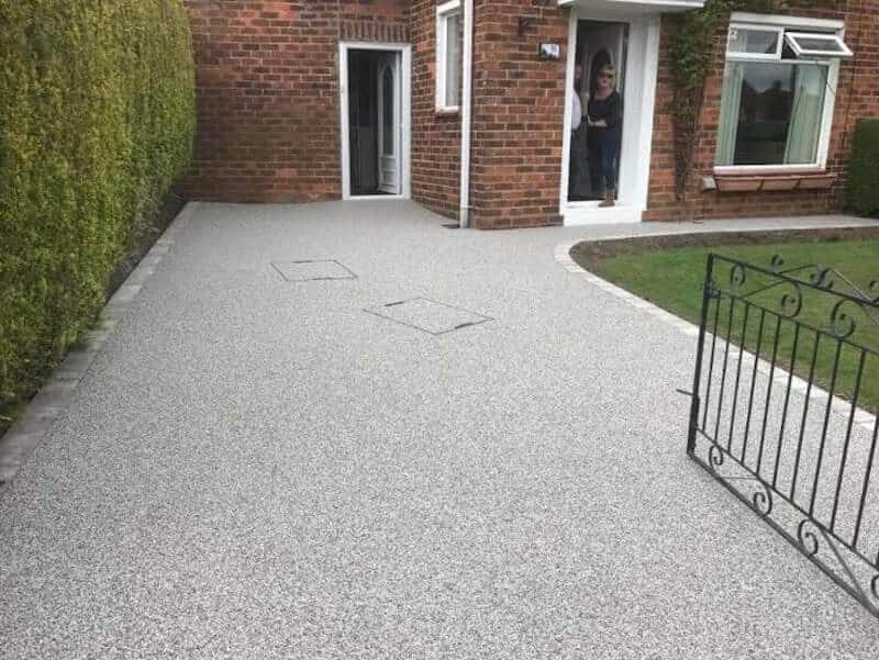 Pale resin driveway with a contrasting edge beside a house