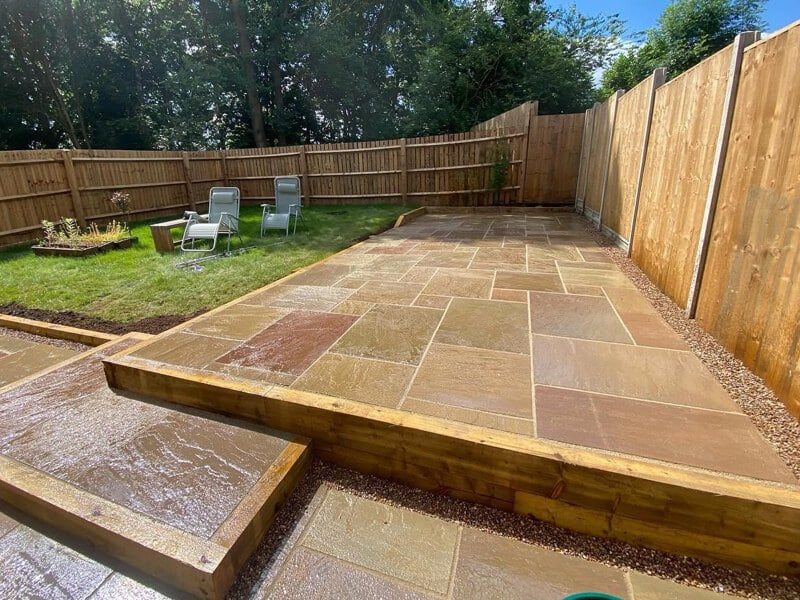 Warm sandstone paving with timber-edged change in level