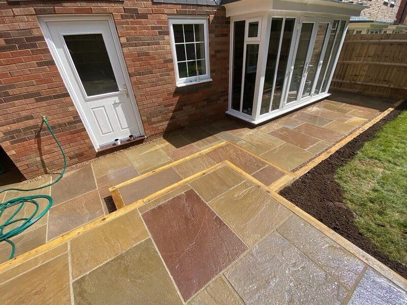 Natural sandstone paving with varied tones beside a house